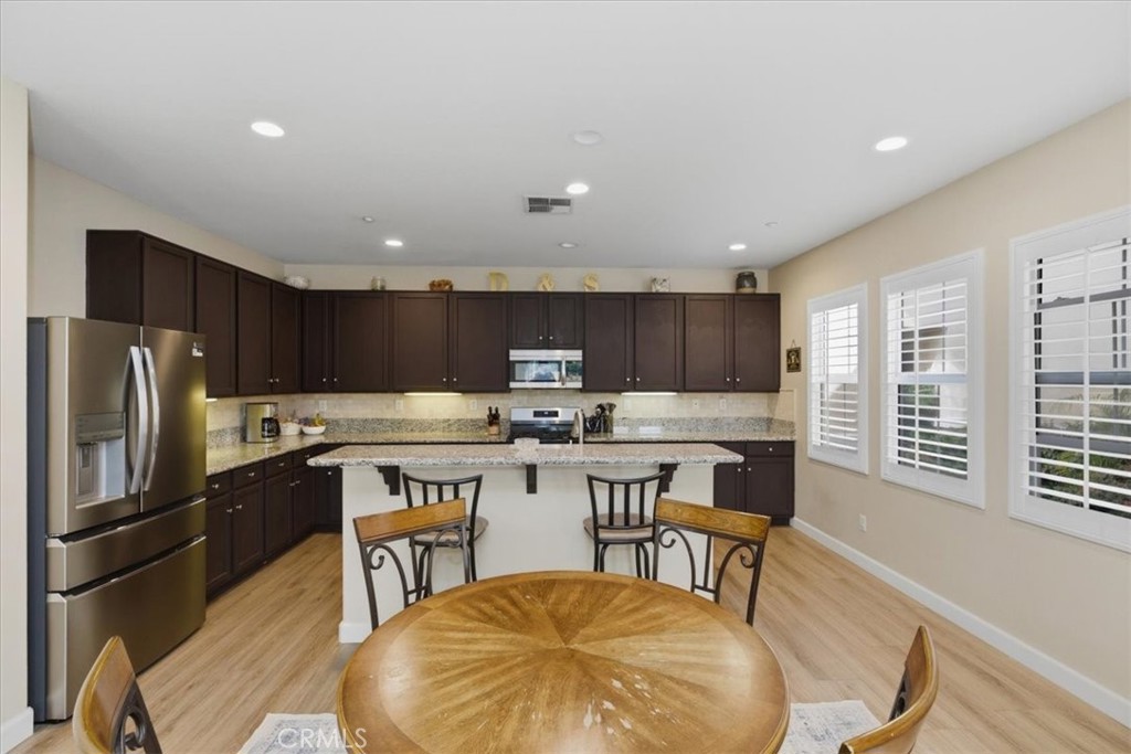 7353 Ellena West, Unit 70 Rancho Cucamonga, CA 91730 - Photo 12 of 40 a kitchen with a table chairs refrigerator and microwave