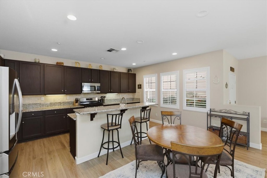 7353 Ellena West, Unit 70 Rancho Cucamonga, CA 91730 - Photo 14 of 40 a kitchen with stainless steel appliances granite countertop a table chairs sink and cabinets
