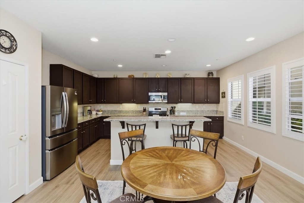 7353 Ellena West, Unit 70 Rancho Cucamonga, CA 91730 - Photo 15 of 40 a kitchen with stainless steel appliances kitchen island granite countertop a kitchen island a stove a table and chairs