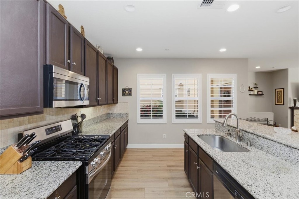 7353 Ellena West, Unit 70 Rancho Cucamonga, CA 91730 - Photo 16 of 40 a kitchen with stainless steel appliances granite countertop a sink stove and cabinets