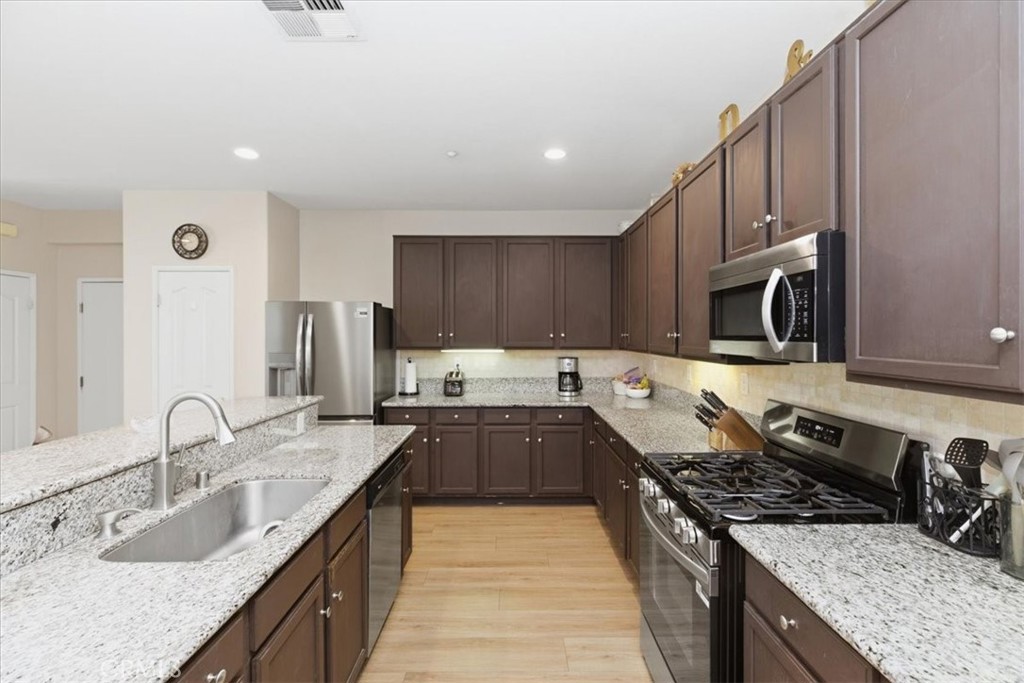7353 Ellena West, Unit 70 Rancho Cucamonga, CA 91730 - Photo 17 of 40 a large kitchen with stainless steel appliances granite countertop a sink stove and refrigerator