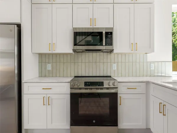 a kitchen with white cabinets and appliances
