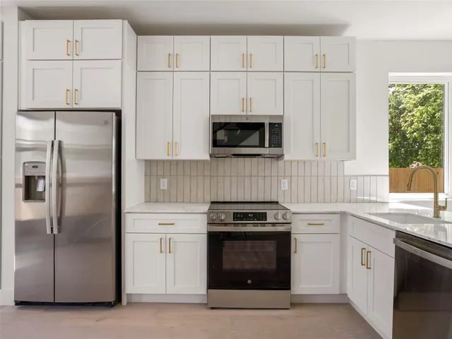 a kitchen with white cabinets and stainless steel appliances