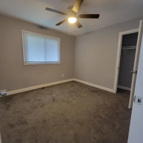 an empty room with windows and fan