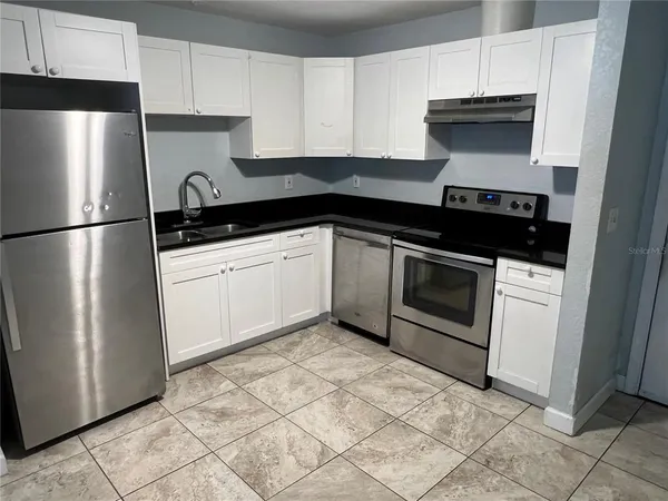 a kitchen with stainless steel appliances a sink a stove a refrigerator and cabinets