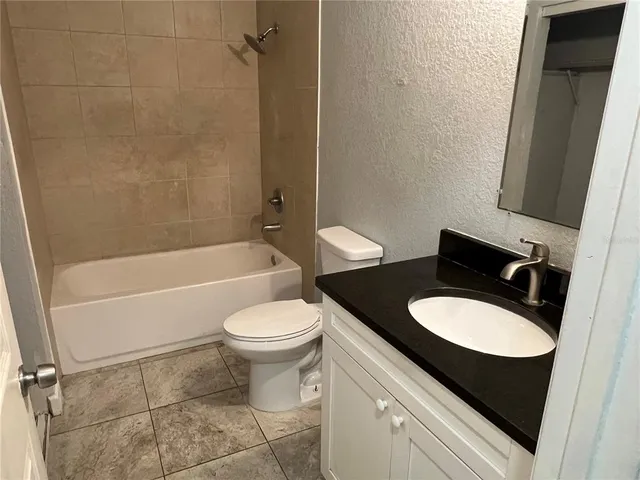 a bathroom with a granite countertop toilet sink and mirror