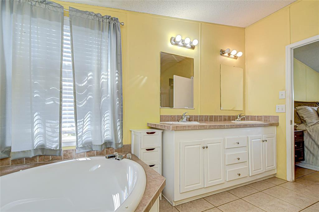 43650 County Road 54 East Kathleen, FL 33849 - Photo 26 of 72 a bathroom with a granite countertop double vanity sink a mirror and a bathtub