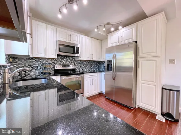 a kitchen with granite countertop a refrigerator and a stove top oven