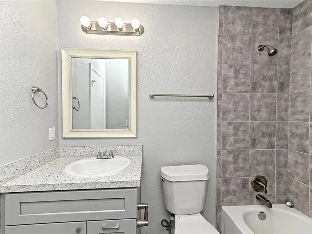 a bathroom with a granite countertop sink a toilet and shower