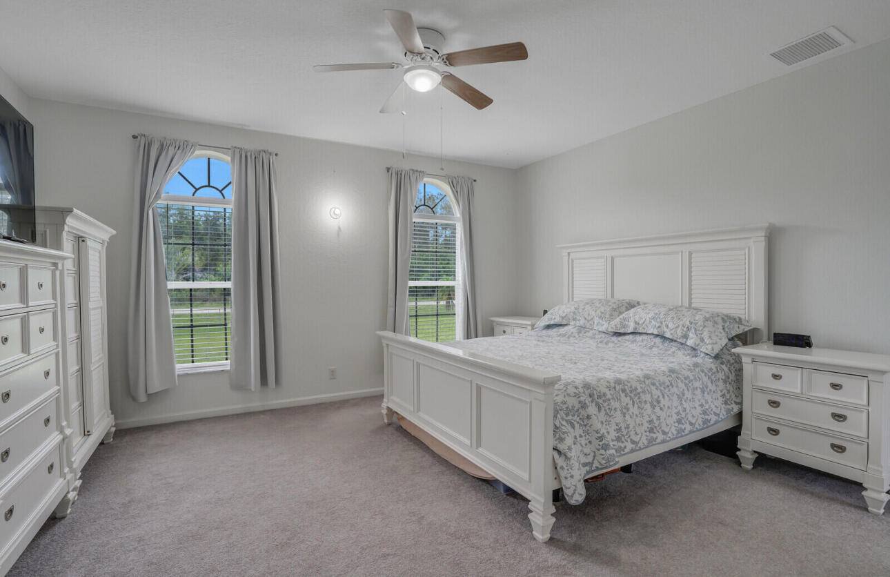 13218 86th Road North The Acreage, FL 33412 - Photo 30 of 69 a spacious bedroom with a bed chandelier and a window