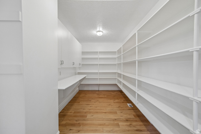 220 East Ridge Road Orem, UT 84057 - Photo 16 of 52 Extensive built-in shelving, white cabinetry with silver hardware, integrated counter space, wood-finish flooring, and overhead lighting