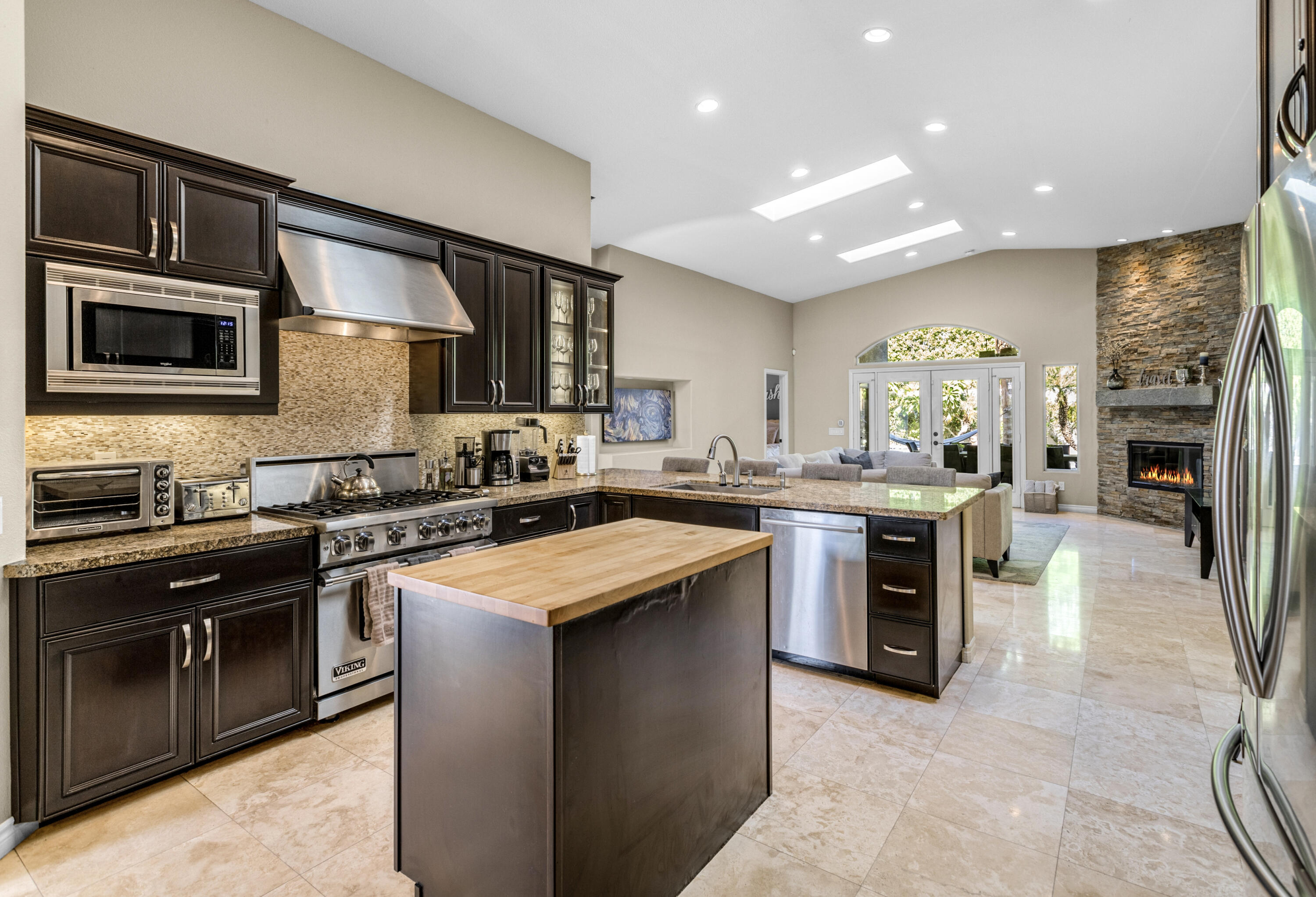 68590 Risueno Road Cathedral City, CA 92234 - Photo 13 of 72 a kitchen with stainless steel appliances granite countertop a stove top oven a sink dishwasher a refrigerator and a dining table with wooden cabinet