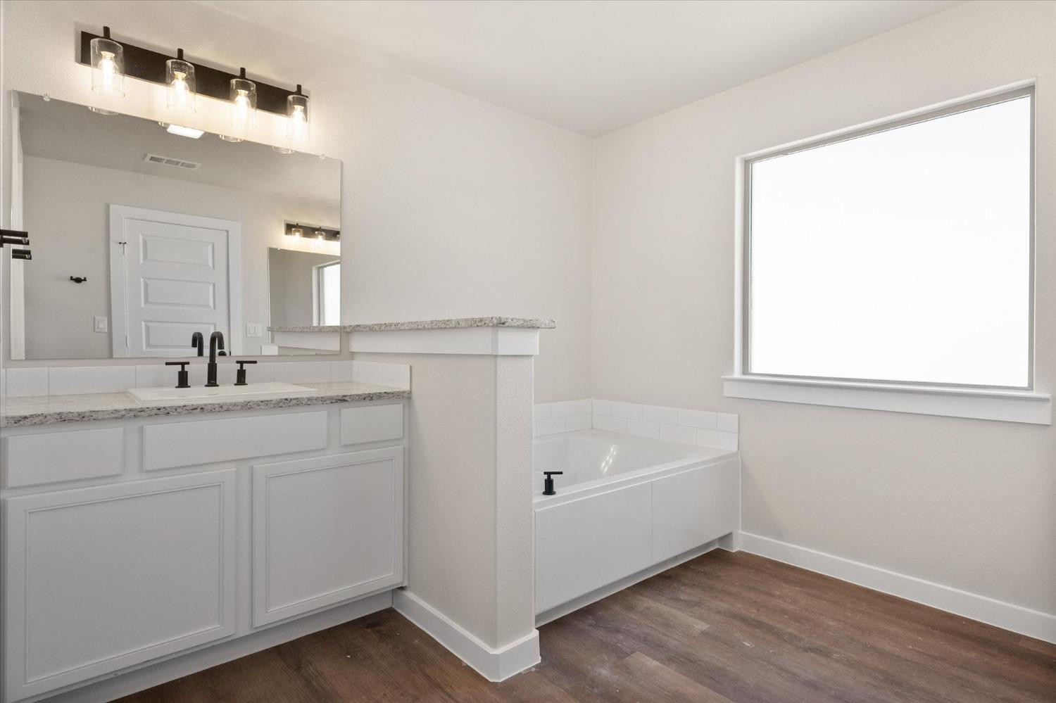 6917 55th Street Lubbock, TX 79407 - Photo 14 of 20 a bathroom with a bathtub a sink and a window