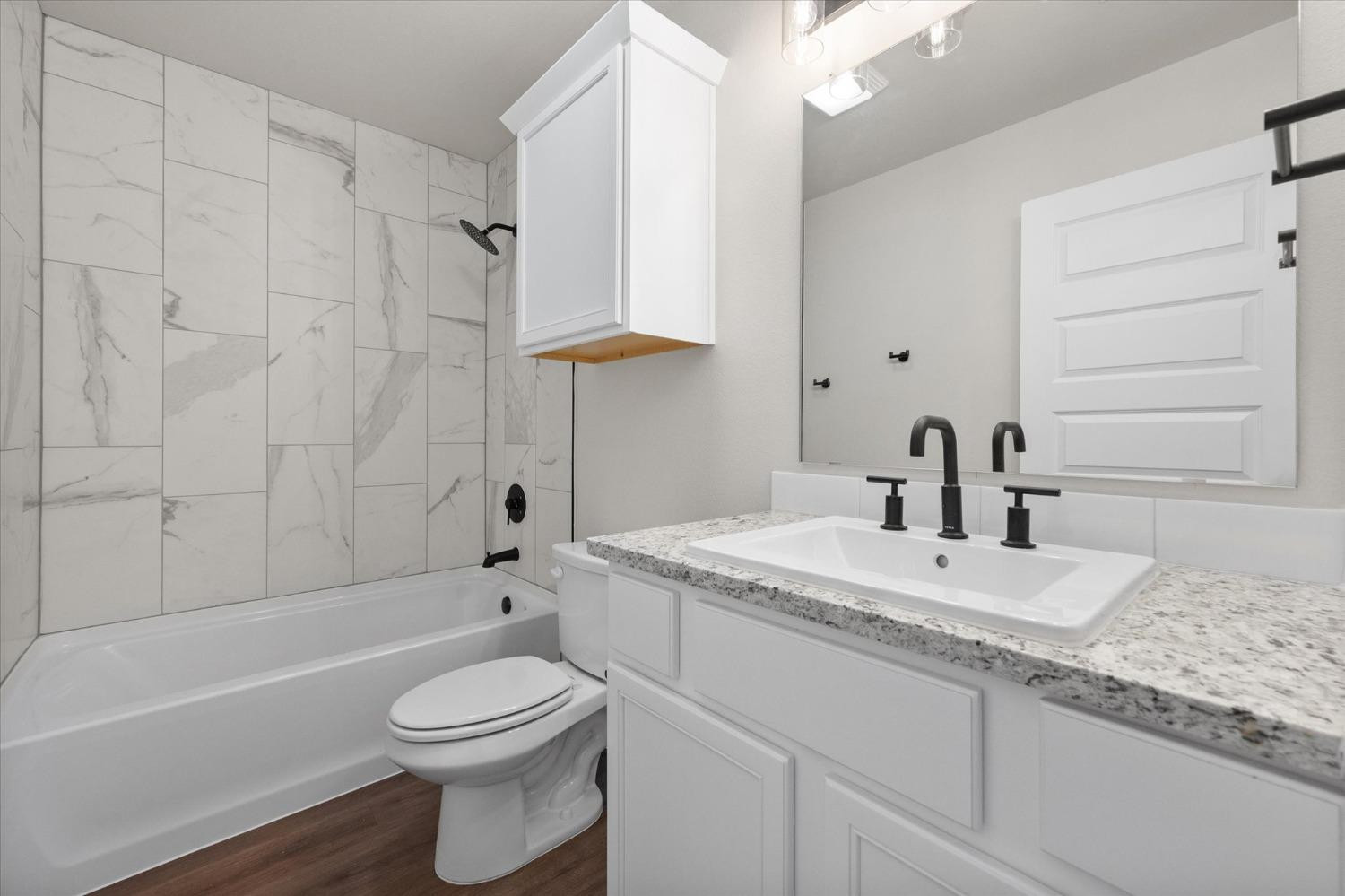 6917 55th Street Lubbock, TX 79407 - Photo 15 of 20 a bathroom with a granite countertop sink a toilet and bathtub