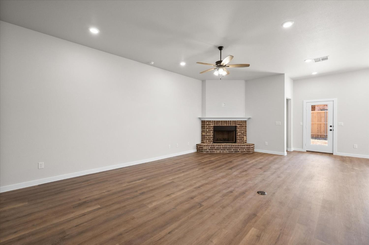 6917 55th Street Lubbock, TX 79407 - Photo 4 of 20 an empty room with wooden floor fireplace and ceiling fan