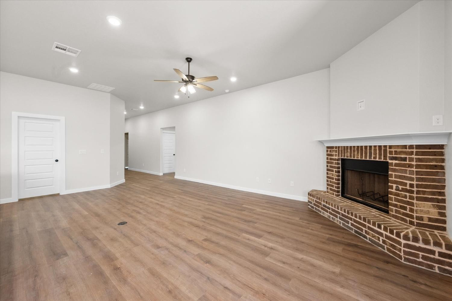6917 55th Street Lubbock, TX 79407 - Photo 5 of 20 an empty room with wooden floor a fireplace and windows