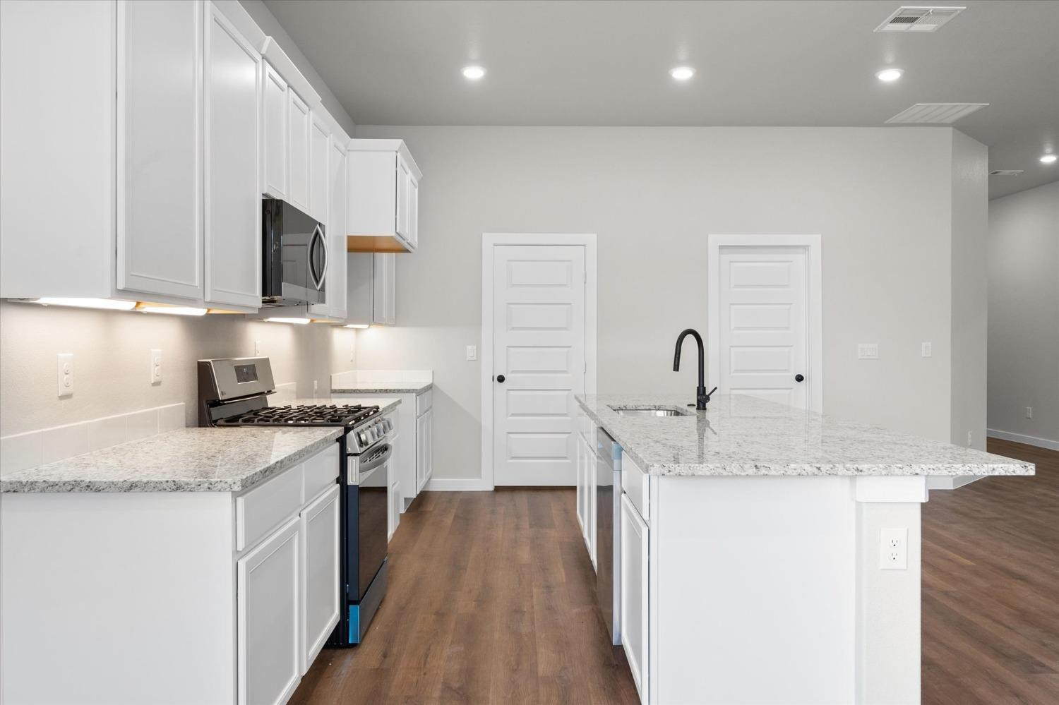 6917 55th Street Lubbock, TX 79407 - Photo 7 of 20 a kitchen with granite countertop a sink stainless steel appliances and white cabinets