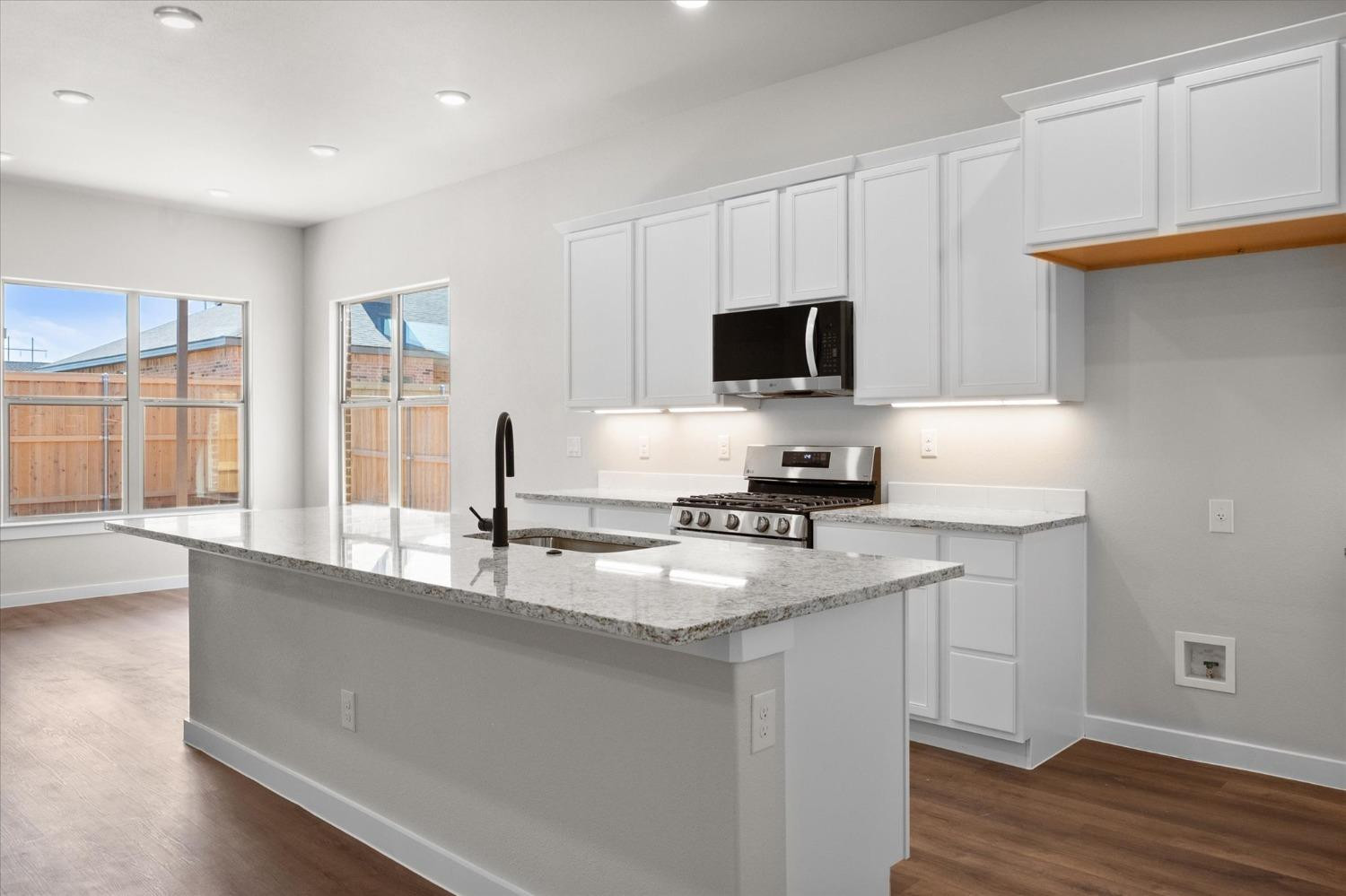 6917 55th Street Lubbock, TX 79407 - Photo 9 of 20 a kitchen with granite countertop a sink and a stove top oven