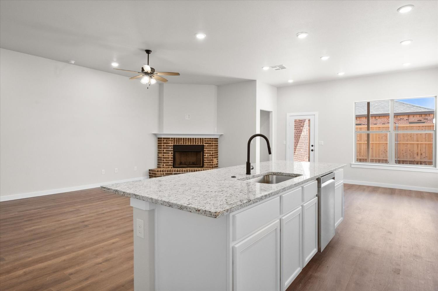 6917 55th Street Lubbock, TX 79407 - Photo 10 of 20 a hall with kitchen island a sink dishwasher a fireplace with wooden floor