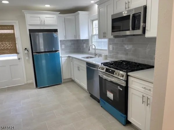 a kitchen with stainless steel appliances granite countertop a stove a microwave a refrigerator a sink and cabinets