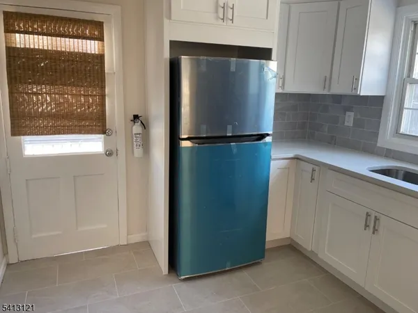 a view of a kitchen with refrigerator and window
