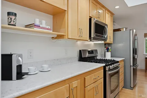 a kitchen with stainless steel appliances granite countertop a sink a stove a microwave and wooden cabinets