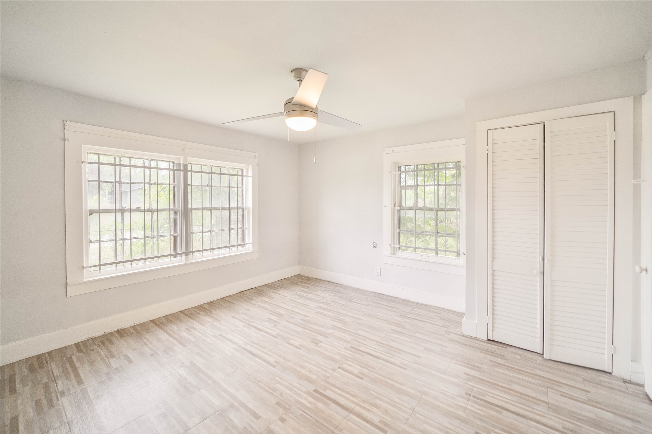 an empty room with wooden floor cabinet and windows