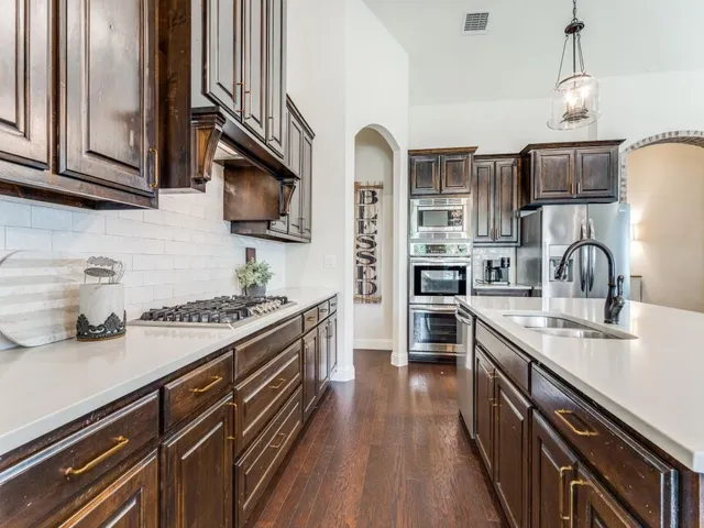 a large kitchen with stainless steel appliances kitchen island granite countertop a table chairs in it and wooden floors