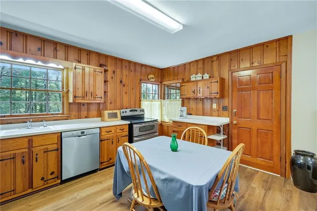 a kitchen with stainless steel appliances granite countertop a stove a refrigerator a sink a dining table and chairs with wooden floor