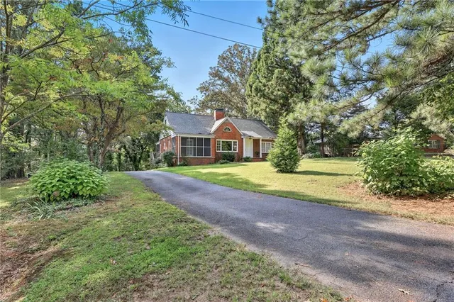 an aerial view of a house with swimming pool and trees all around