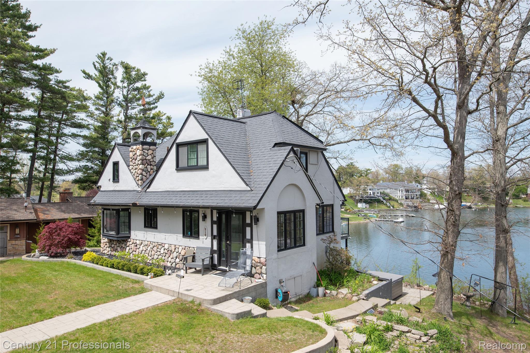 910 West Pine Tree Road West Lake Orion, MI 48362 - Photo 4 of 52 Tudor house with stucco siding, covered porch, stone siding, a front yard, and a water view