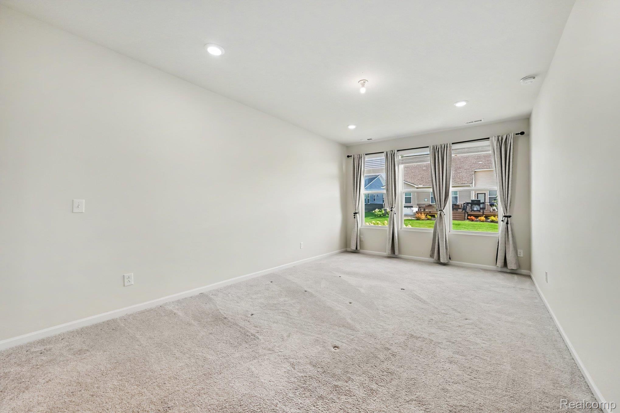 50153 Fowler Road Canton, MI 48188 - Photo 13 of 27 Recessed lighting, three windows with draperies, neutral wall color, and light-toned carpeting