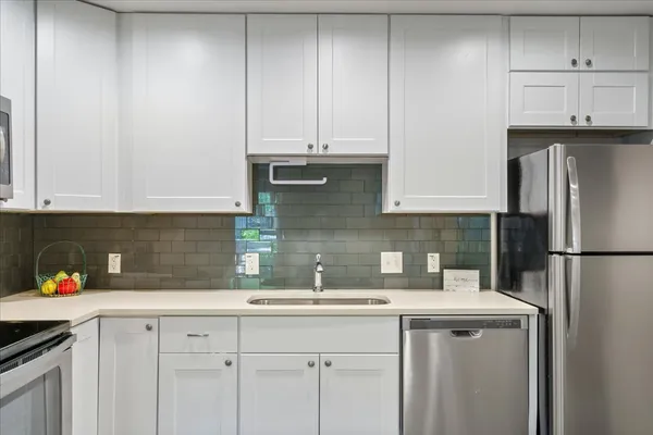 a kitchen with stainless steel appliances granite countertop a refrigerator a stove a sink and white cabinets