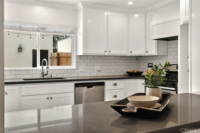 a kitchen with a sink dishwasher and white cabinets with wooden floor