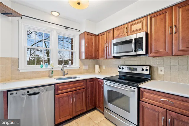 a kitchen with cabinets stainless steel appliances a sink and a window