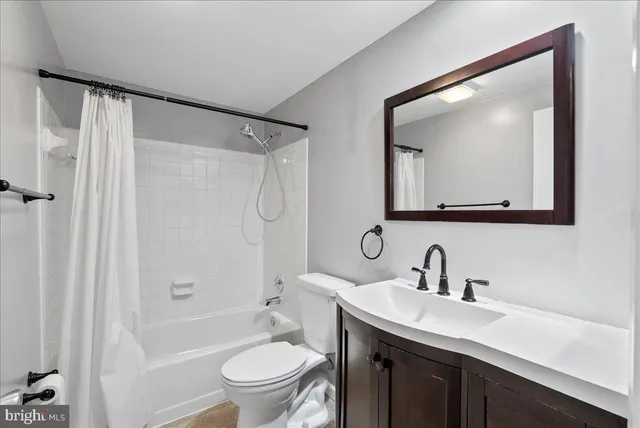 a bathroom with a toilet a sink a mirror a bathtub and vanity