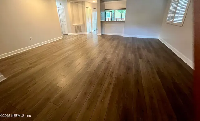 an empty room with wooden floor and windows