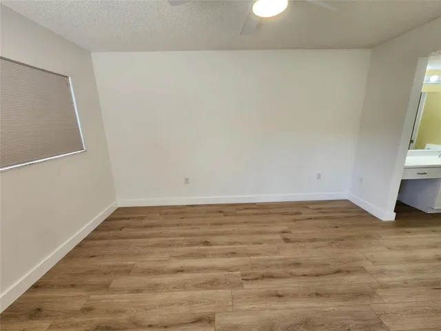 an empty room with wooden floor and fan
