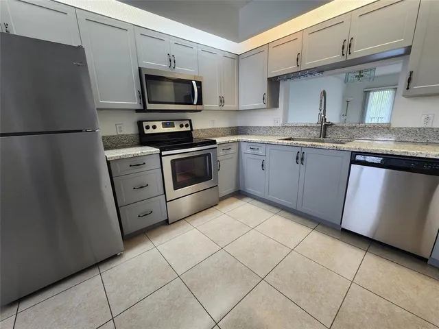 a kitchen with stainless steel appliances granite countertop a refrigerator sink and stove