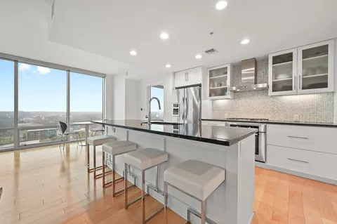 a dining hall with stainless steel appliances granite countertop a stove and a kitchen view