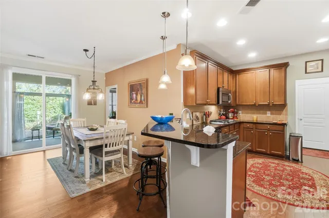 a kitchen with stainless steel appliances kitchen island granite countertop a table chairs and a refrigerator