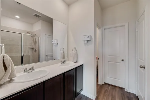 a bathroom with a double vanity sink a mirror and a shower