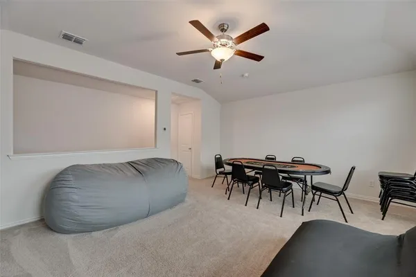 a dining room with furniture and a chandelier fan