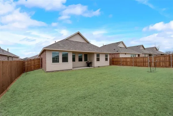 a view of a yard in front of a house with a large tree