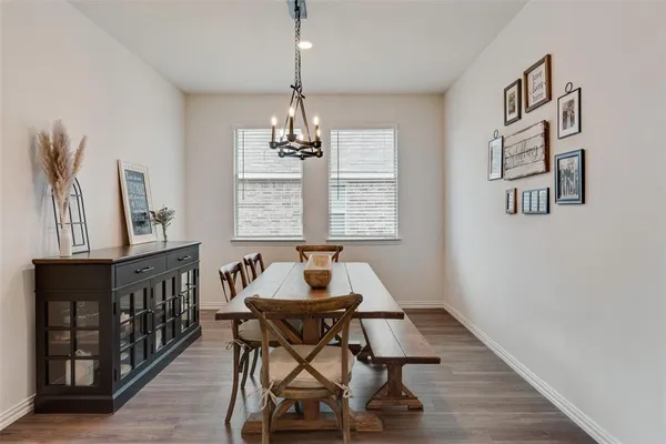a dining room with wooden floor a chandelier a wooden table and chairs