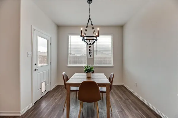 a dining room with chandelier and wooden floor