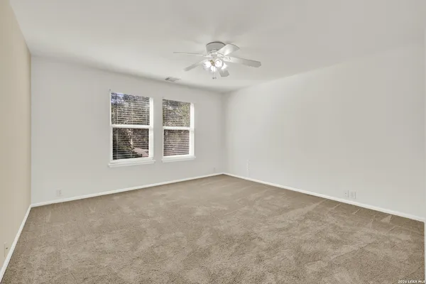 a view of an empty room with chandelier fan and fire place