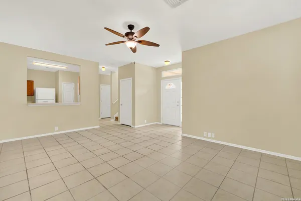 a view of an empty room and chandelier fan
