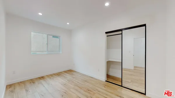 a view of an empty room with wooden floor and closet