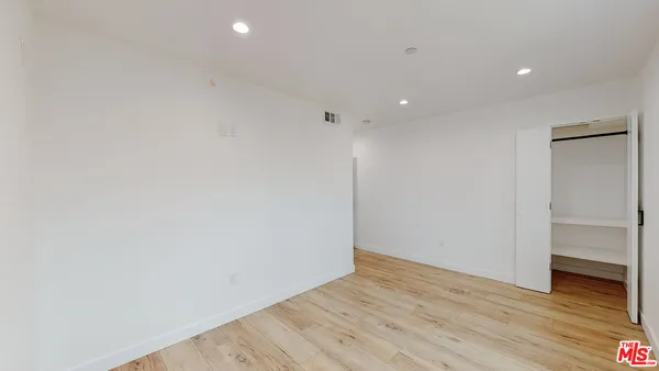 a view of an empty room with wooden floor and closet